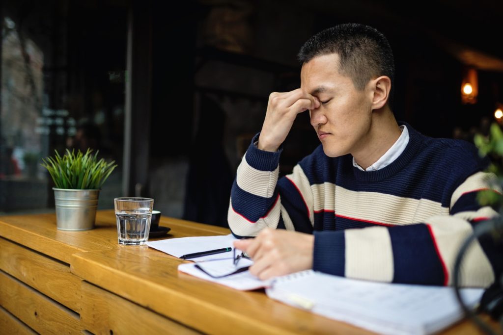 Joven trabajador autónomo japonés exitoso organizando su tiempo mientras está sentado en un café